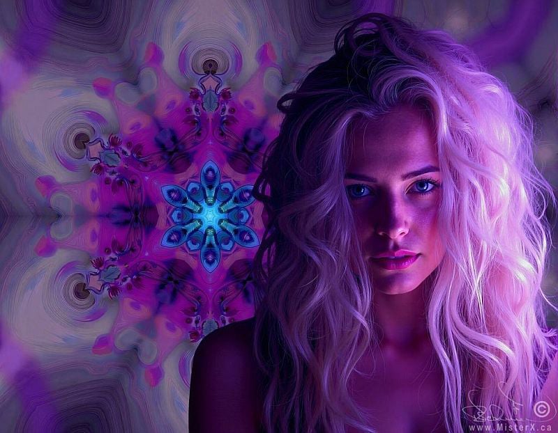 This enchanting digital portrait features a young woman with a captivating, soft gaze, framed by voluminous, wavy platinum-blonde hair that catches the vibrant light. Her face and hair are illuminated by a striking split-lighting effect, casting a deep magenta glow on one side and a cool, electric violet on the other. In the background, an intricate, kaleidoscopic mandala composed of purple, blue, and pink crystalline geometric layers radiates outward, acting as a psychedelic halo. The composition blends hyper-realistic features with surreal, neon-drenched tones, creating a dreamy, cyberpunk-inspired atmosphere that emphasizes themes of mystery and inner transformation